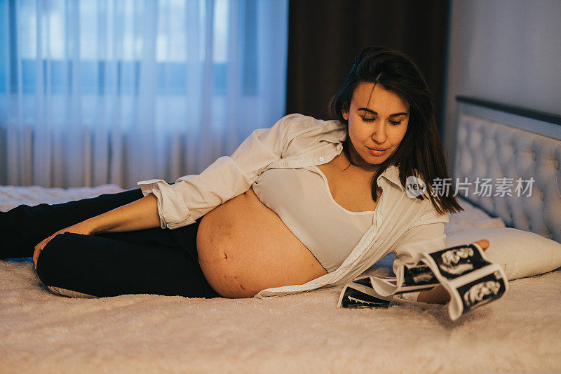 孕妇在床上抱着超声波扫描图像