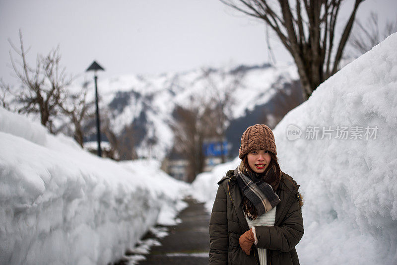 美丽的年轻女子走在堆积的雪地上