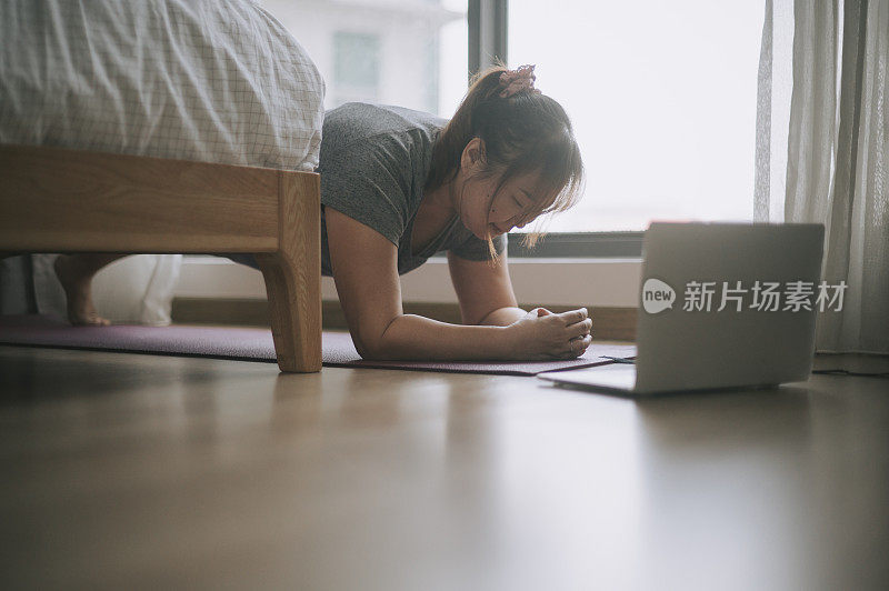 亚洲中国身体积极的女性在周末在家学习用笔记本电脑做俯卧撑