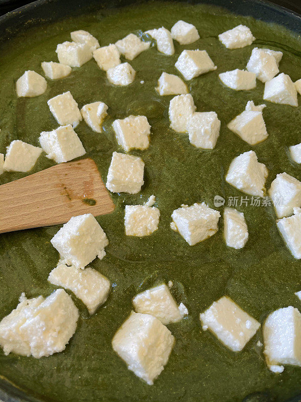 用木铲在不粘锅里搅拌素食帕拉克奶酪(白软干酪和菠菜泥)的全景图