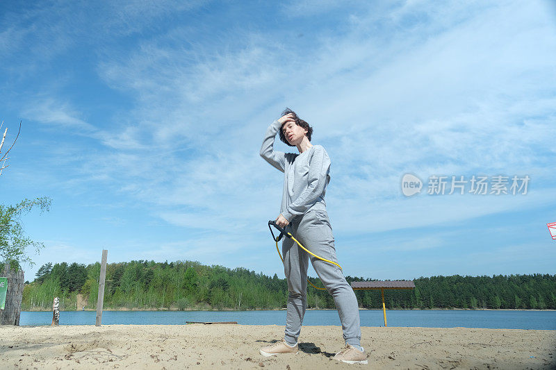 成熟的女人在湖边和抵抗乐队一起锻炼