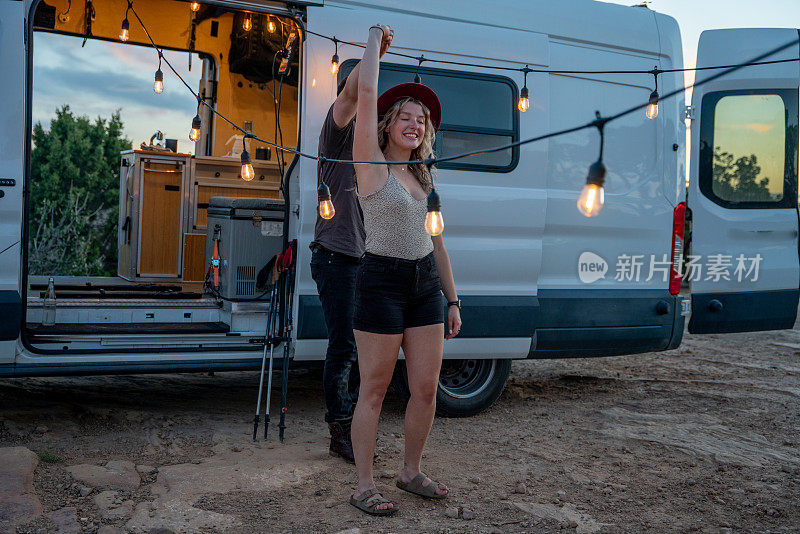 黄昏时分，一对幸福的情侣在沙漠里的露营车里一起跳舞