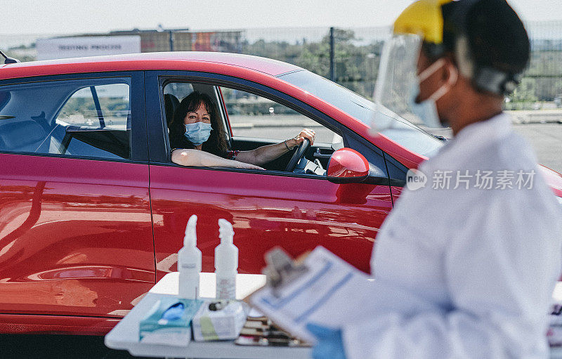 一个蒙面妇女在外面的汽车餐厅测量温度