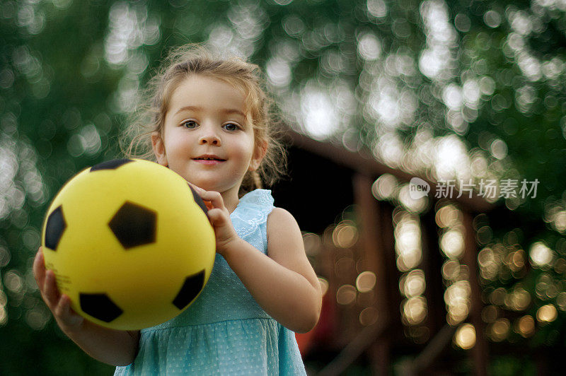 小女孩捧着足球，脸上带着幸福的笑容。