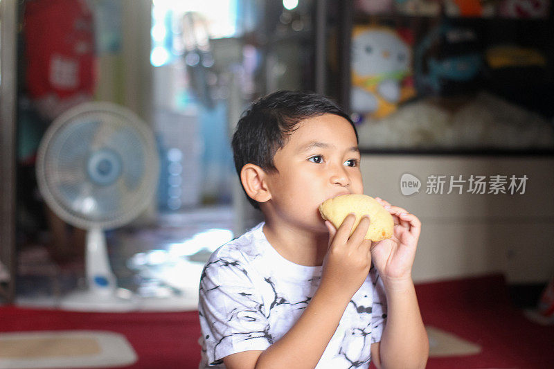 男孩坐在家里吃面包