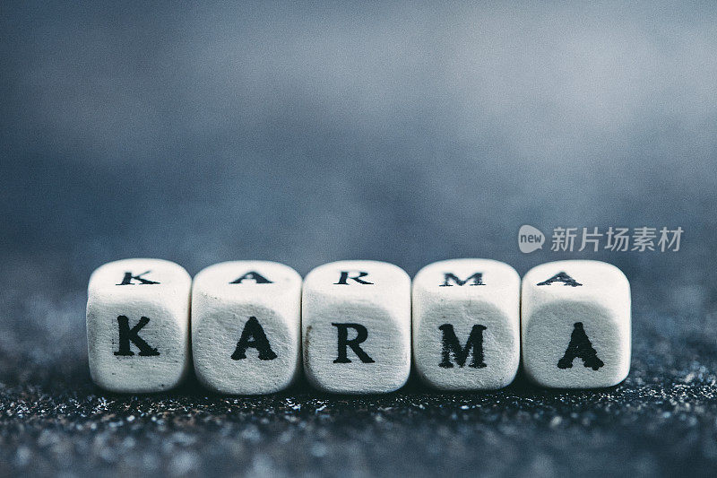 字母表在深灰色的桌子上阻止拼写单词KARMA。使用复制空间拍摄