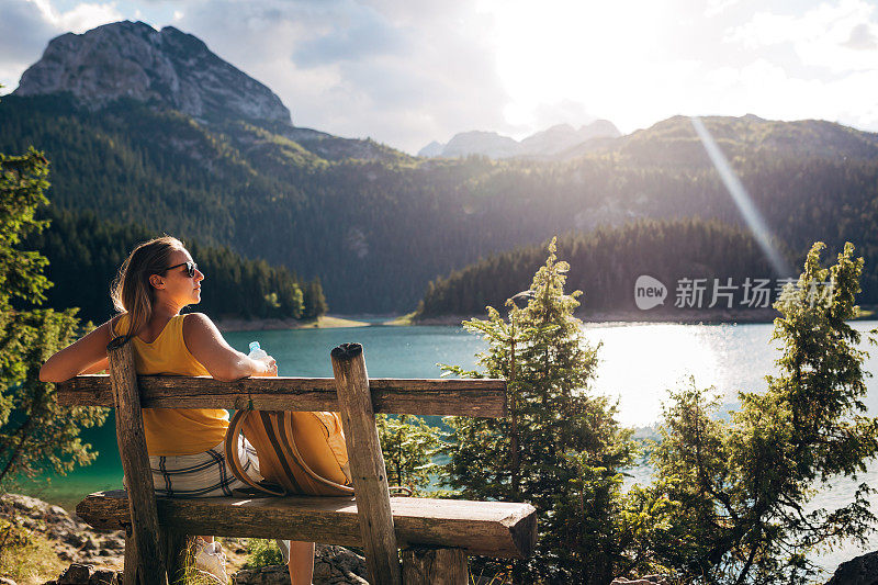 一个女人坐在瞭望台的木凳上，俯瞰着整个湖。