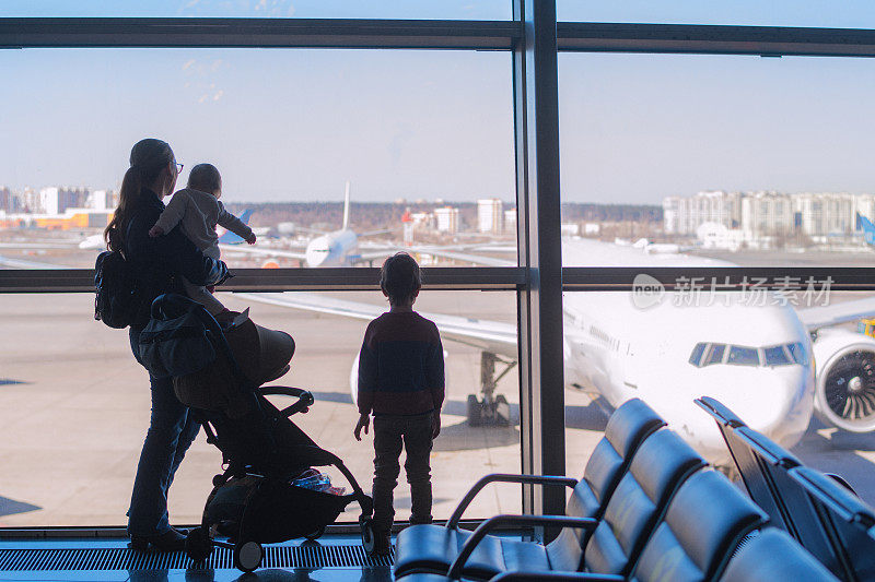 小男孩，小女孩和他们的妈妈在机场透过窗户看飞机