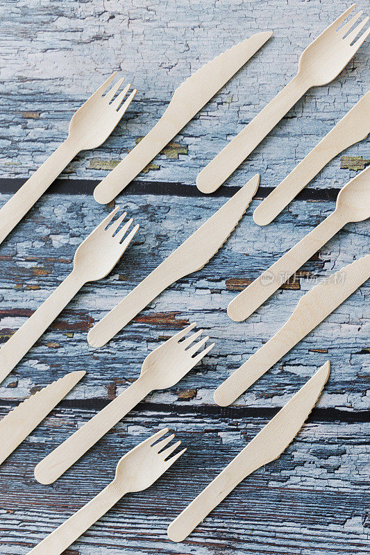 浅蓝色木制背景上的环保餐具平面组合。牛皮纸盘子和木制餐具。可回收的纸制品，零浪费的理念。有选择性的重点