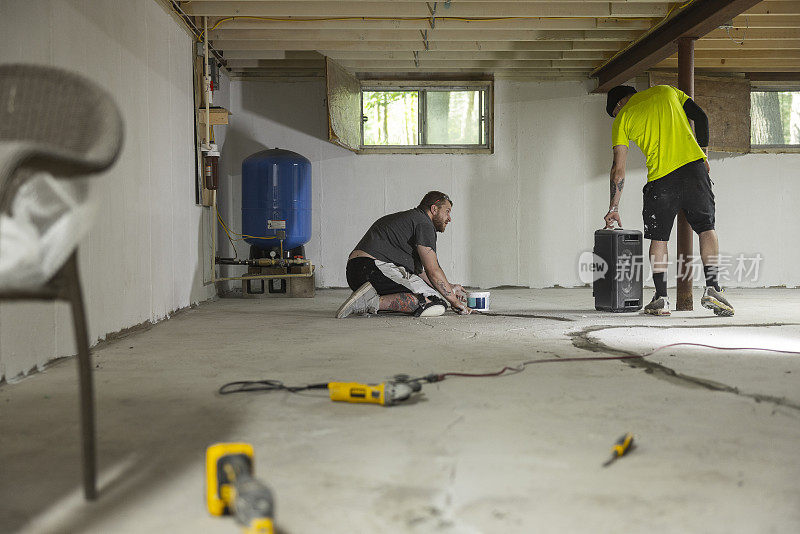 白人工人用防水水泥密封地下室地板的裂缝。