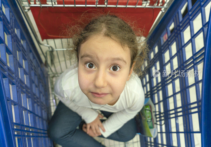 一个小女孩在超市里坐着手推车