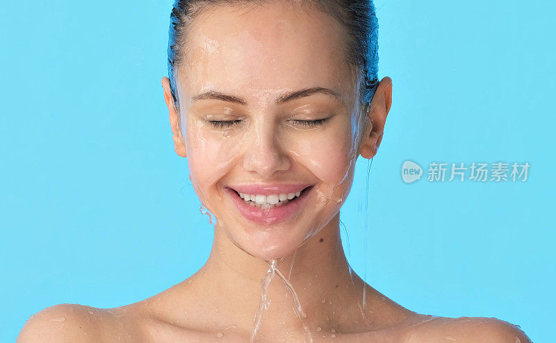 女性脸上有水。年轻快乐的女孩，脸上淌着水。女子用水洗干净的脸。