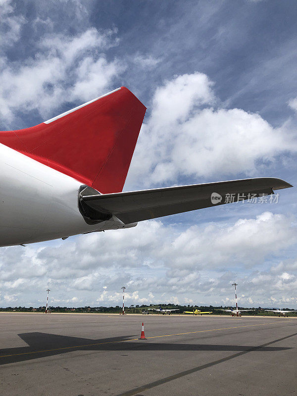 飞机的后翼是焦点前景在停机坪垂直照片
