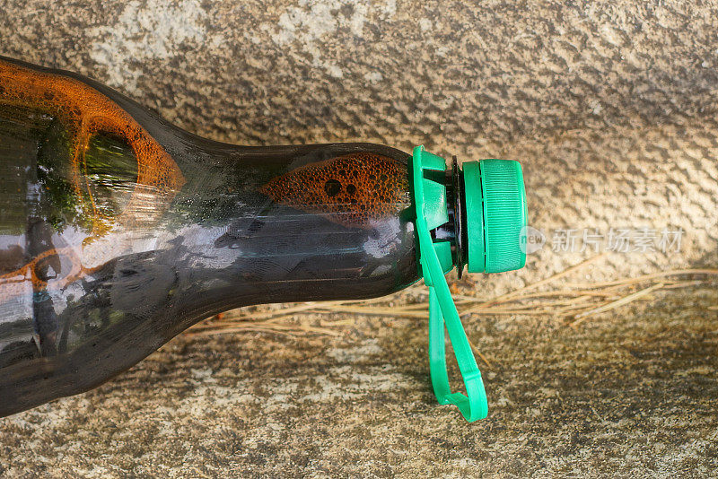 一个棕色塑料瓶的一部分，装着啤酒，用绿色的软木塞封着