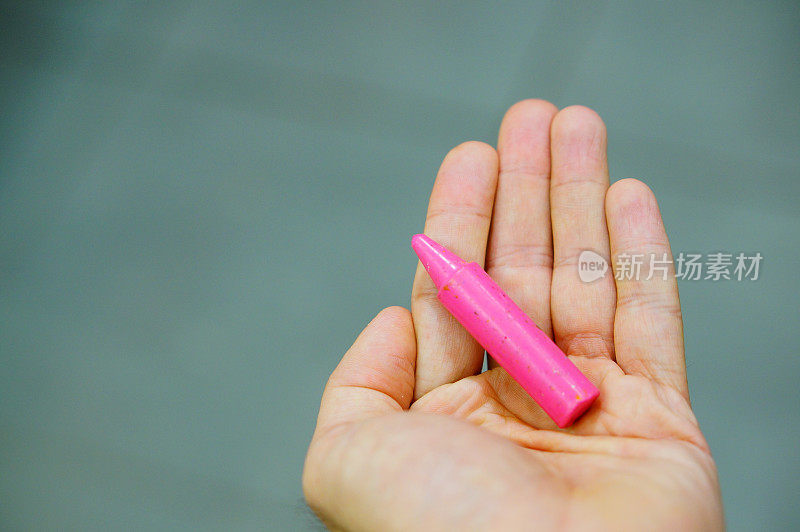 一只手上的粉色蜡笔的特写镜头