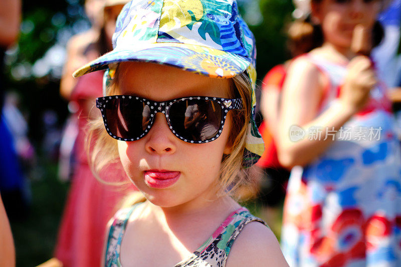 可爱的夏天肖像小女孩看着相机戴着她妈妈的太阳镜