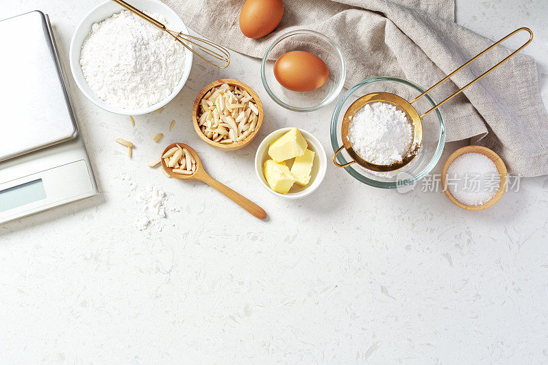 烘焙和烹饪原料，黄油，面粉，鸡蛋和杏仁条，大理石背景上的数字秤