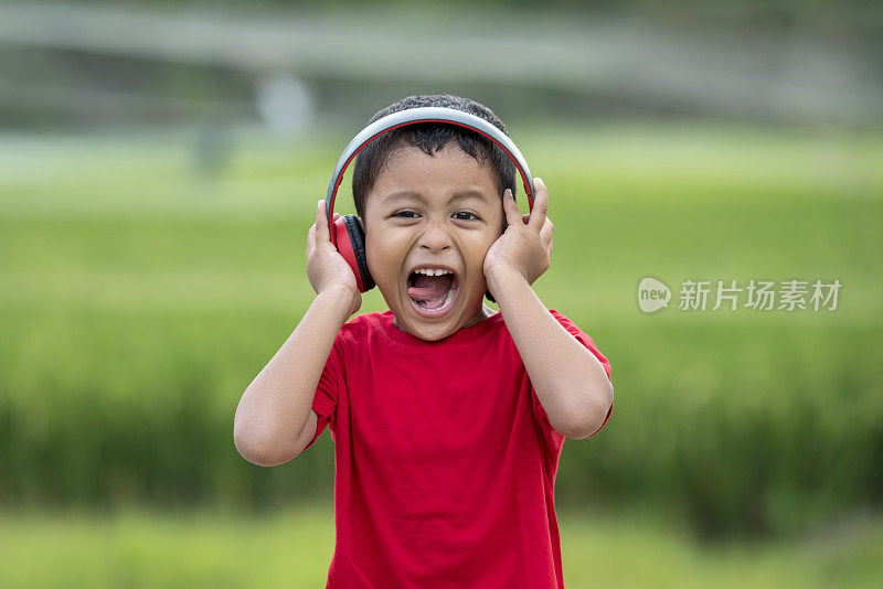 蹒跚学步的男孩用耳机听音乐