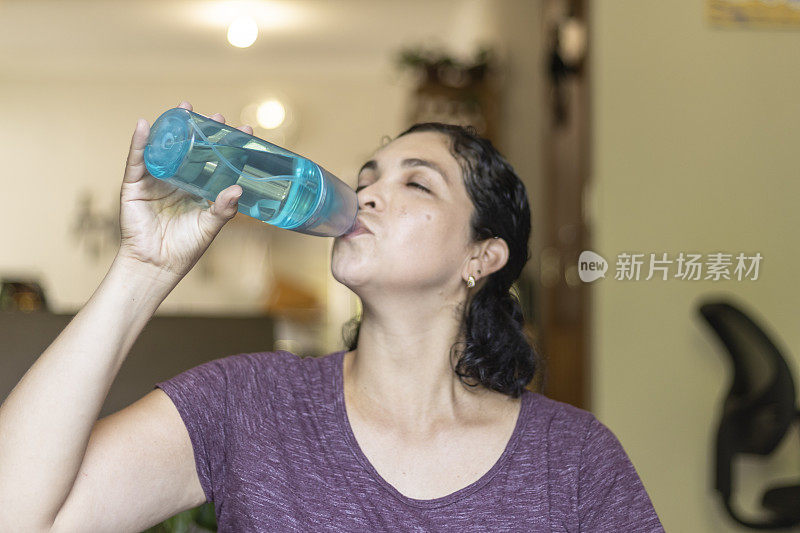 一名拉丁妇女在瑜伽运动后用瓶子喝水