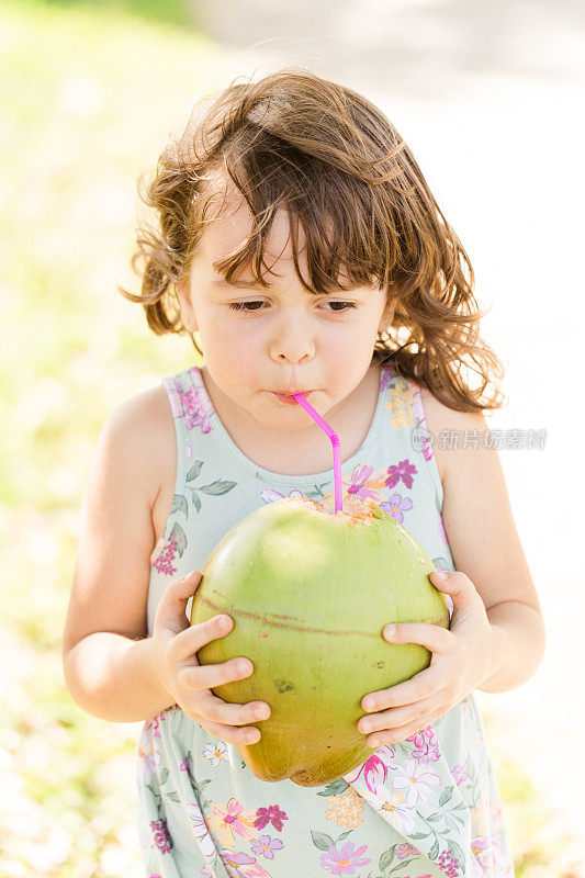 2023年春天，一个4岁的小女孩和家人一起享受简单的快乐，第一次体验新鲜收获的椰子的味道，在温暖的南佛罗里达户外用粉红色的吸管喝椰子水