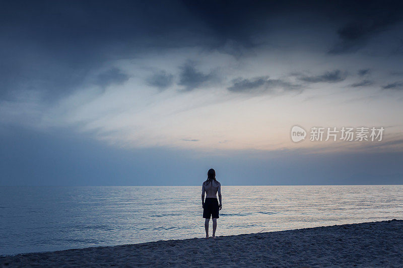 人的剪影映衬着清晨的天空。海上日落