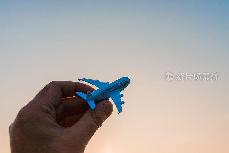 手里拿着玩具飞机的人，有梦想想成为一名飞行员。背景上模糊了云，太阳湛蓝的天空。