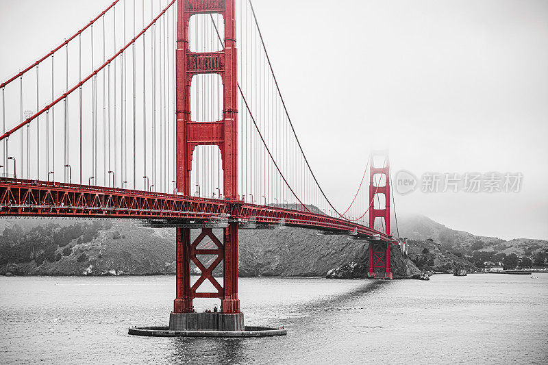 大雾天气中的旧金山金门大桥，一张保留了红色的黑白照片。