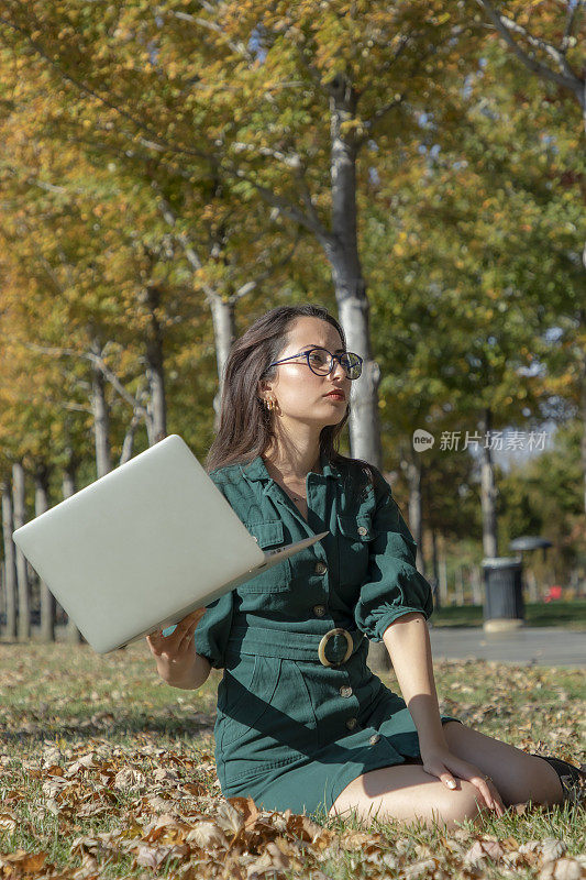 一个年轻的黑发女人在公园里摆弄她的电脑