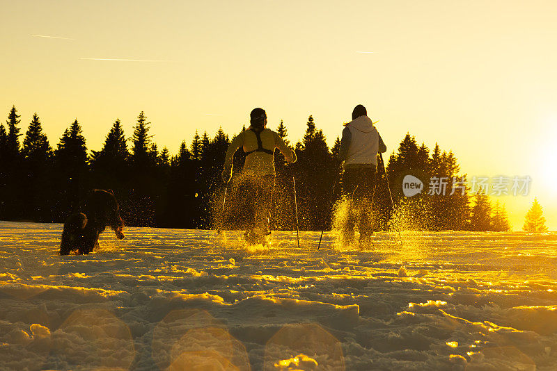 滑雪者带着宠物狗在雪坡上奔跑的剪影