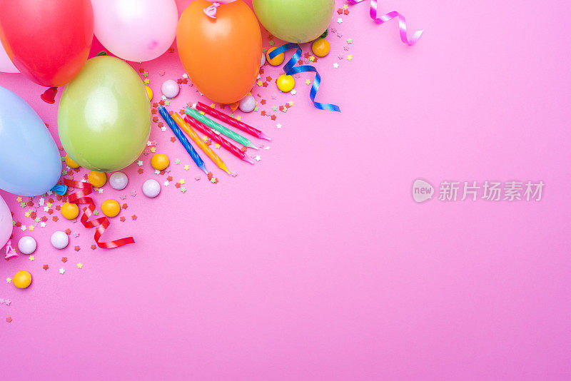 派对气球，生日蜡烛和五彩纸屑边界粉红色的背景。本空间