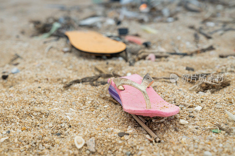 近距离拍摄的沙滩上散落着各种塑料制品，导致海滩环境严重污染。被丢弃的塑料制品对海岸生态系统造成了有害影响。