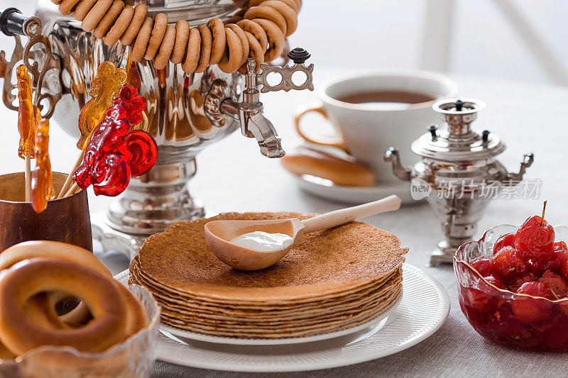 俄罗斯的传统。俄罗斯节日Maslenitsa。还有一杯茶，一堆煎饼，酸奶油，蜂蜜，黄油块，百吉饼，干果，焦糖鸡和茶具。