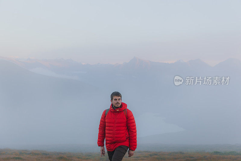 前视图的一个人考虑日落徒步到湖之上的云在挪威的山区