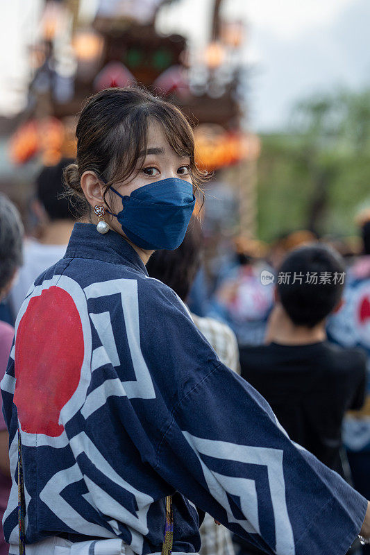 年轻女子在传统的日本服装在看肩在matsuri