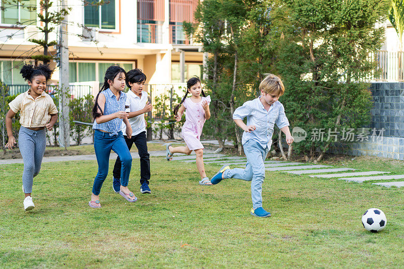 一群孩子在学校的花园里一起踢足球。可爱的男孩和女孩的孩子足球队感到快乐和放松，追逐球享受有趣的活动在小学。