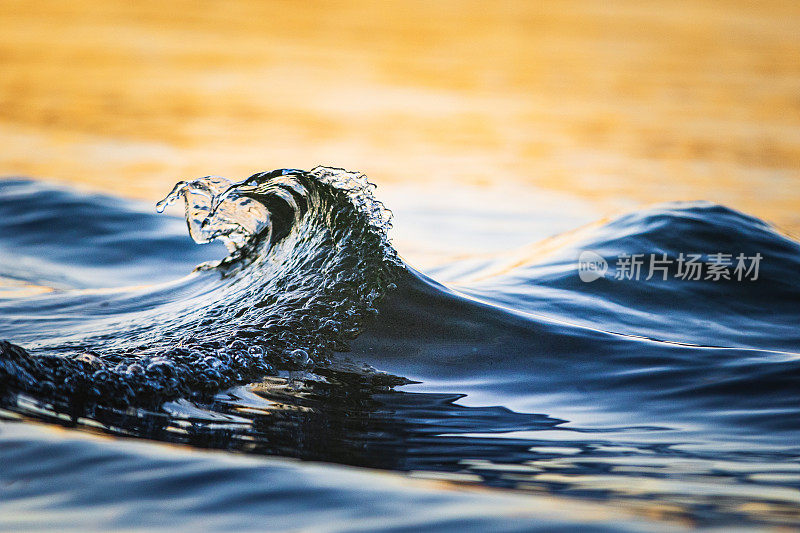 小小的抽象的波浪在海岸线上溅起金色的光