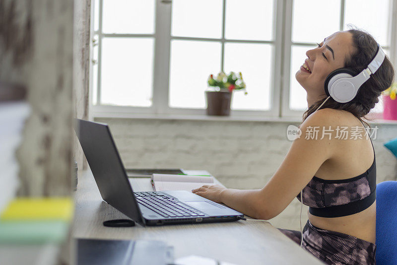 一个穿着运动服的年轻女子正在家里用笔记本电脑进行视频通话