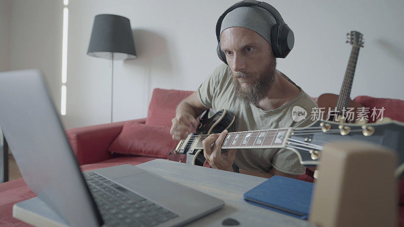 一个人在笔记本电脑上视频聊天弹吉他，和乐队在网上排练