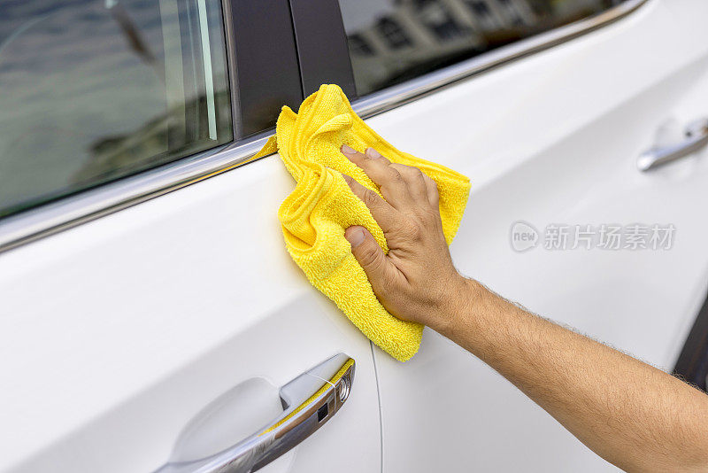 一名男子正在用一块布清洗他的汽车