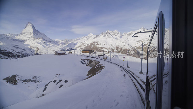 火车在冰雪覆盖的轨道上行驶在冬季的山景中。马特洪峰，瑞士阿尔卑斯山