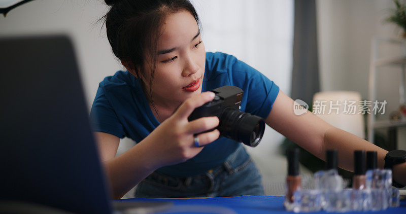 年轻的女摄影师在家庭摄影棚里整理产品