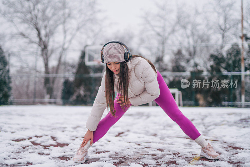 冬季，女运动员站在大自然的雪地上做热身运动