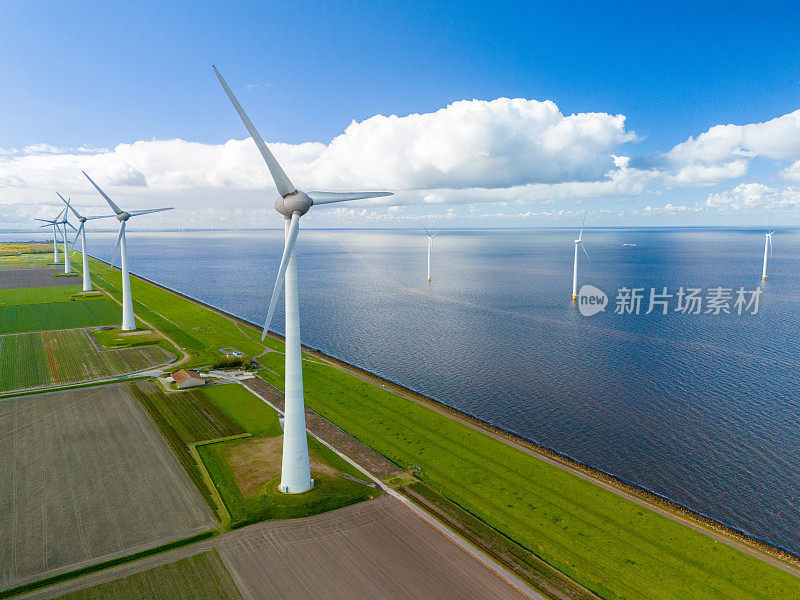 荷兰一个巨大湖泊中央的风力发电场生产清洁能源，成排的风车涡轮机在春天的天空下优雅地旋转