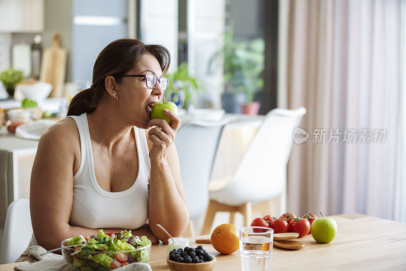 健康饮食理念。一个女人咬着苹果吃着沙拉