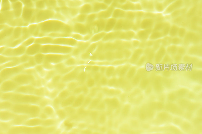 水表面。橘黄色的水波在水面上泛起模糊的涟漪。透明的蓝色颜色清澈平静的水面纹理飞溅和泡沫。波光粼粼的水波。