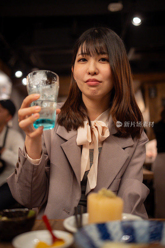 下班后在日本居酒屋酒吧喝酒的年轻女商人