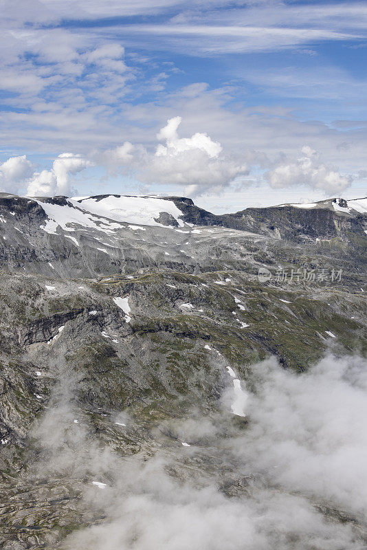 最后的积雪在七月的阳光下逐渐融化，在通往1500米高的Geirangerfjord天空步道的挪威山边。