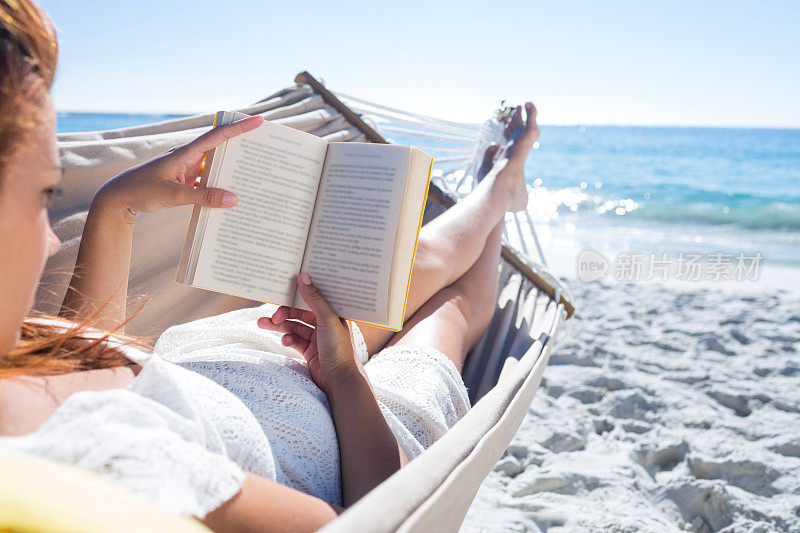 褐发女人一边在吊床上放松一边看书