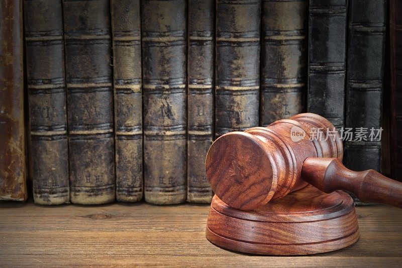 木制法官的木槌和木制背景下的旧法律书籍