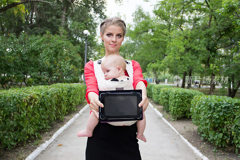 带着婴儿屏幕笔记本电脑的女人。